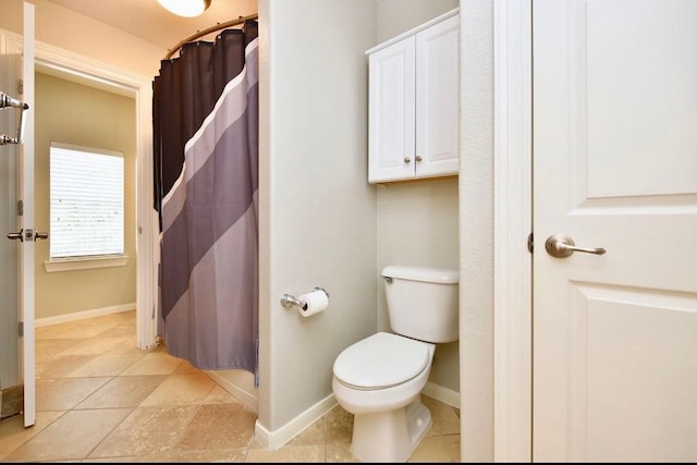 bathroom featuring a shower with shower curtain, toilet, baseboards, and tile patterned floors