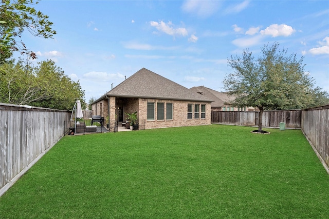 rear view of house featuring a yard, a fenced backyard, brick siding, and roof with shingles