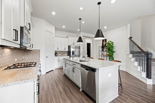 kitchen with a sink, a kitchen breakfast bar, dark wood-style floors, white cabinetry, and stainless steel appliances