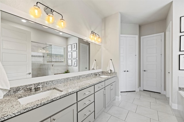 full bathroom featuring tile patterned flooring, double vanity, tiled shower, and a sink