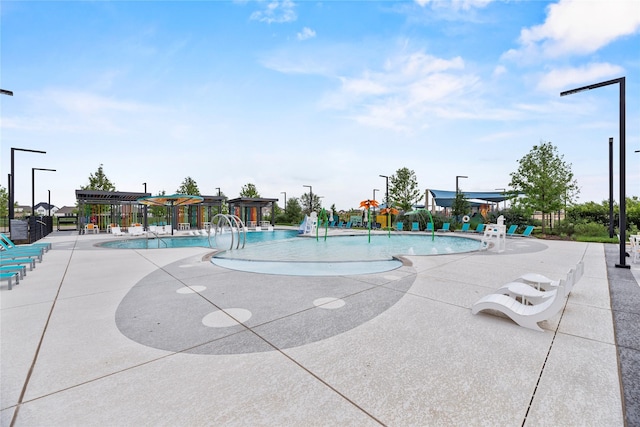 pool featuring a water play area, a water slide, a patio, and fence