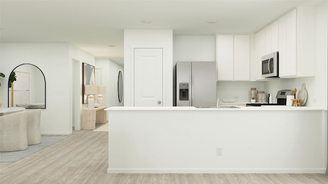 kitchen with sink, light hardwood / wood-style flooring, stainless steel appliances, white cabinets, and kitchen peninsula