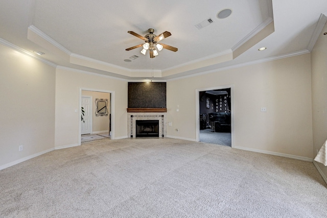 unfurnished living room with crown molding, ceiling fan, a fireplace, light colored carpet, and a raised ceiling