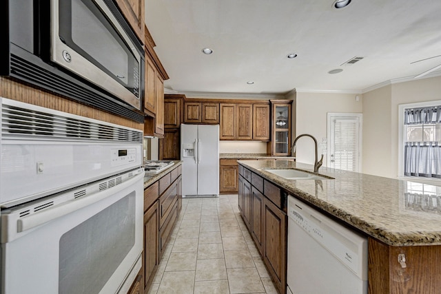 kitchen with sink, light tile patterned floors, ornamental molding, stainless steel appliances, and a kitchen island with sink