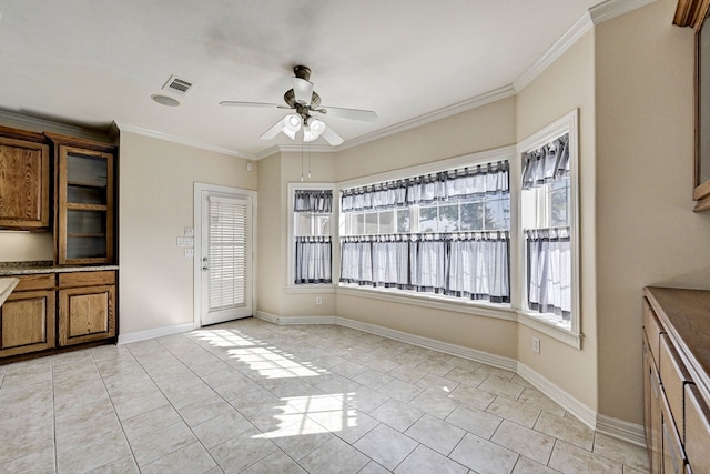 unfurnished dining area with light tile patterned floors, ornamental molding, and ceiling fan