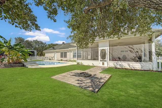 back of property with a patio, a yard, a fenced in pool, and a fire pit