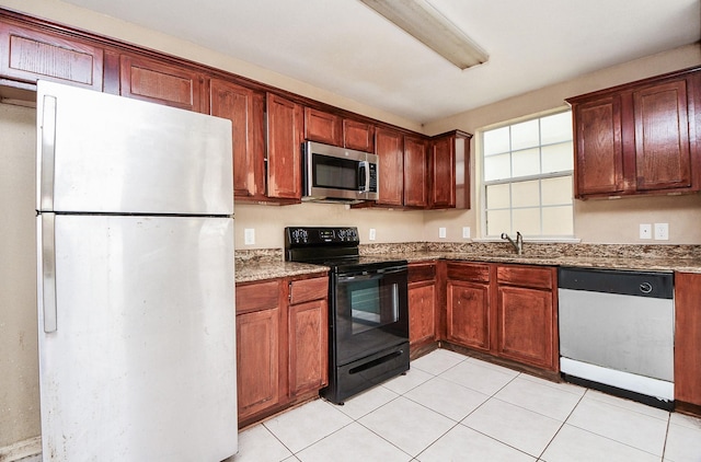 kitchen with stone counters, stainless steel microwave, electric range, freestanding refrigerator, and dishwashing machine