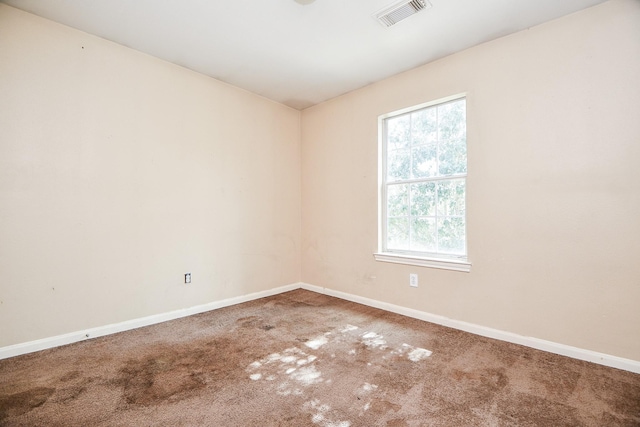 empty room with carpet, visible vents, and baseboards