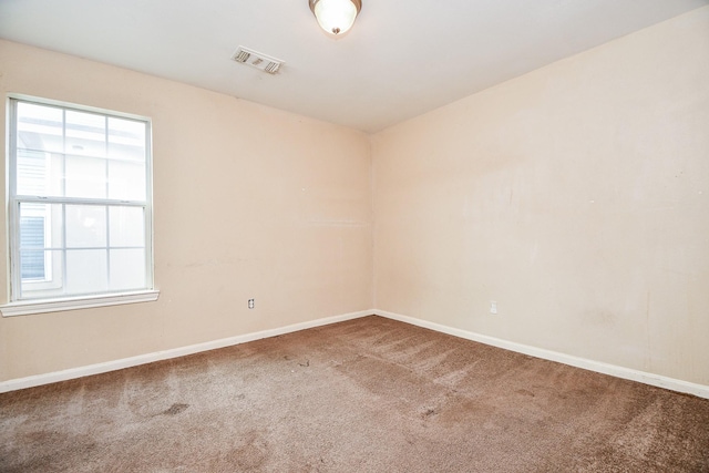 spare room featuring carpet floors, visible vents, and baseboards