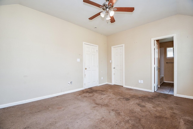 unfurnished bedroom featuring carpet floors, ensuite bath, baseboards, and vaulted ceiling