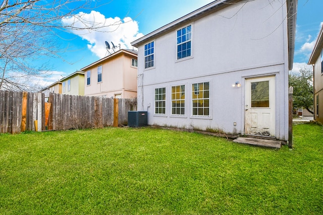 back of house with stucco siding, a yard, fence, and central AC unit