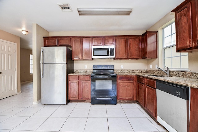 kitchen with visible vents, light stone countertops, stainless steel appliances, a sink, and light tile patterned flooring