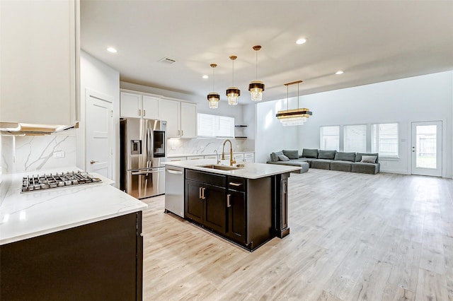 kitchen with sink, hanging light fixtures, stainless steel appliances, light stone countertops, and white cabinets