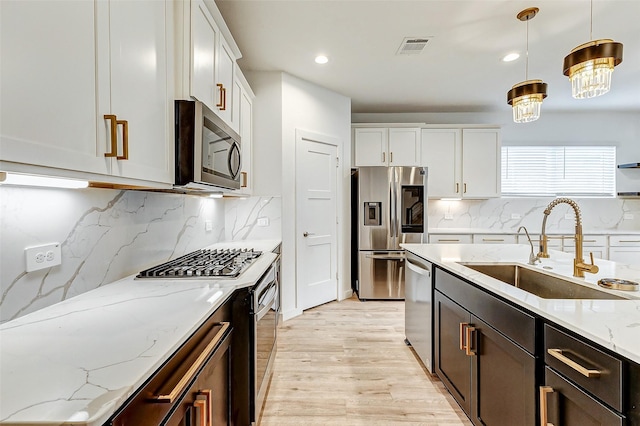 kitchen with white cabinetry, stainless steel appliances, sink, and pendant lighting