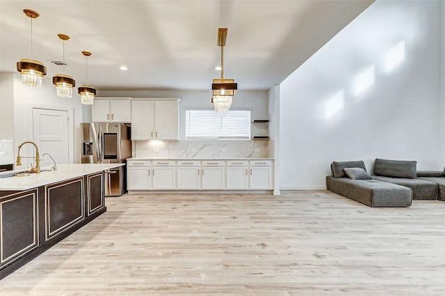 kitchen featuring sink, light wood-type flooring, white cabinets, pendant lighting, and backsplash