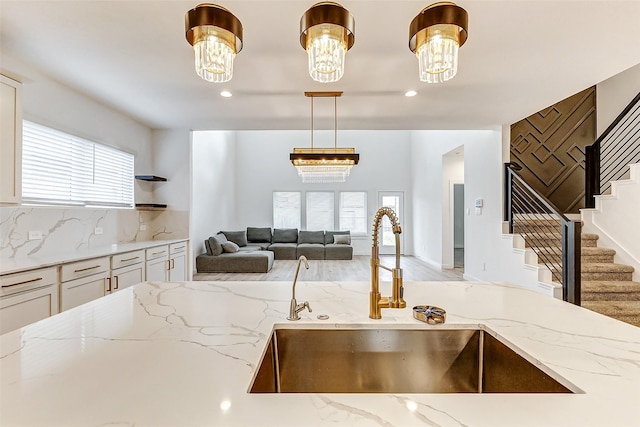 kitchen featuring pendant lighting, sink, light stone counters, and a wealth of natural light