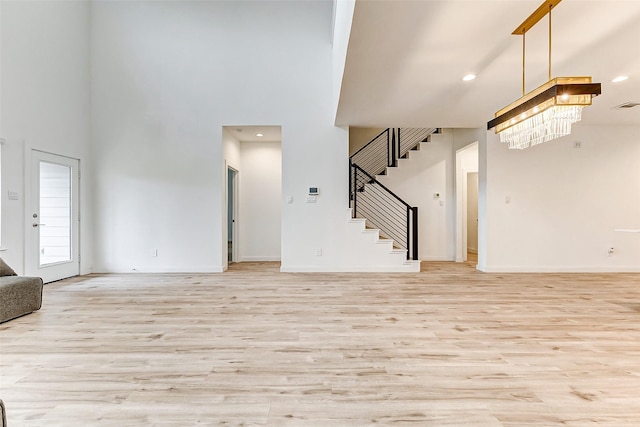 unfurnished living room featuring a towering ceiling and light hardwood / wood-style flooring