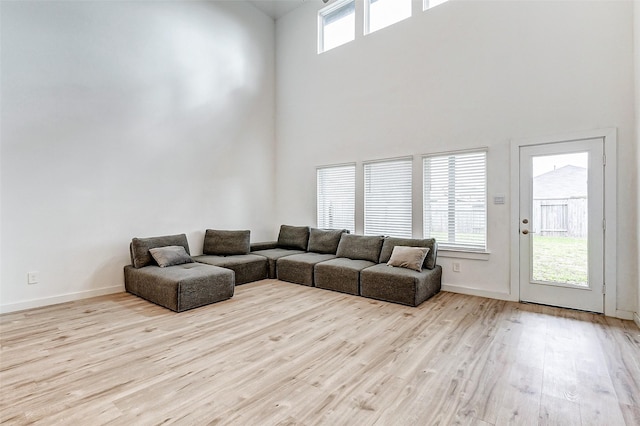 living room featuring a towering ceiling, light hardwood / wood-style flooring, and plenty of natural light