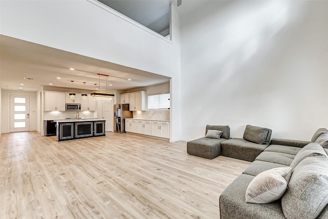 living room with light hardwood / wood-style floors and a high ceiling