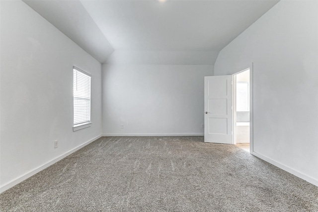 carpeted spare room with vaulted ceiling