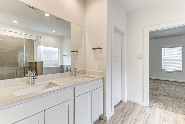 bathroom featuring vanity, a healthy amount of sunlight, hardwood / wood-style floors, and a shower with shower door