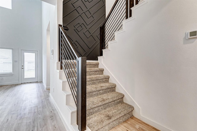 stairs with hardwood / wood-style flooring and a high ceiling