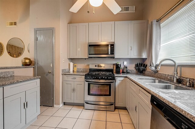 kitchen featuring sink, light tile patterned floors, appliances with stainless steel finishes, light stone counters, and white cabinets