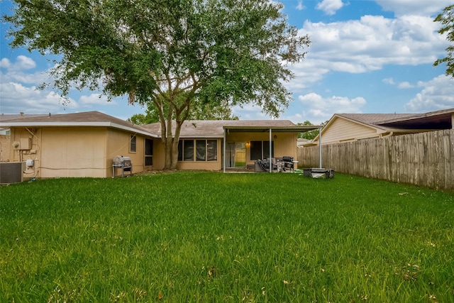 back of property with central air condition unit and a lawn