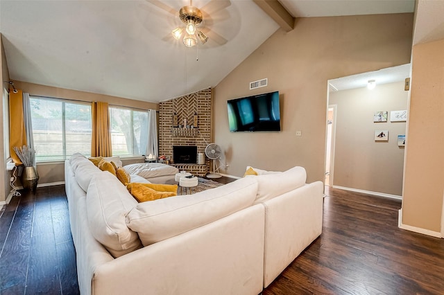 living room with dark wood-type flooring, ceiling fan, beam ceiling, and a brick fireplace