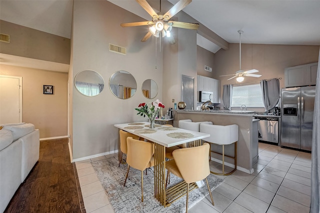 tiled dining space featuring high vaulted ceiling and ceiling fan