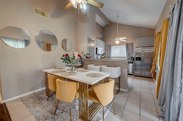 tiled dining space with high vaulted ceiling and ceiling fan