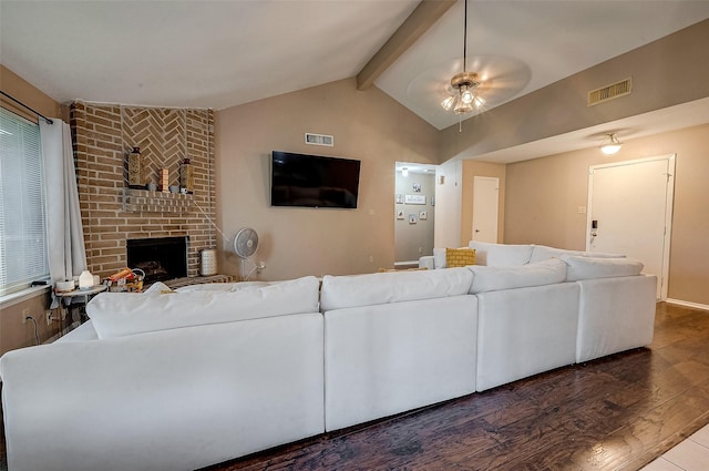 living room featuring dark wood-type flooring, ceiling fan, lofted ceiling with beams, and a brick fireplace