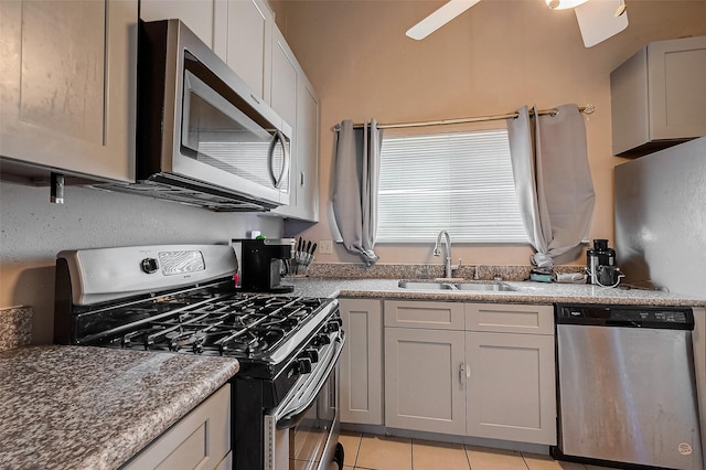 kitchen featuring sink, dark stone countertops, light tile patterned floors, appliances with stainless steel finishes, and gray cabinets