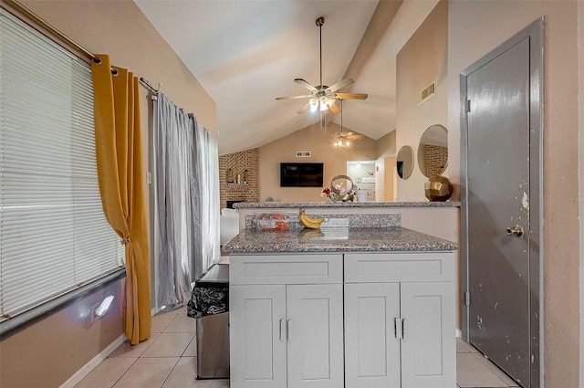 kitchen featuring vaulted ceiling, light tile patterned floors, stone counters, ceiling fan, and white cabinets