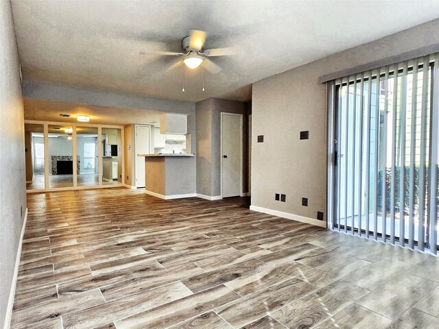 unfurnished living room with light wood-type flooring and ceiling fan