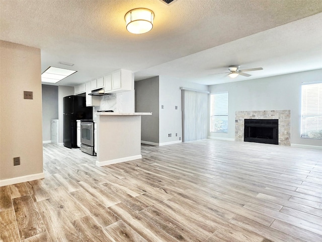 kitchen with white cabinetry, black fridge, kitchen peninsula, ceiling fan, and light hardwood / wood-style floors