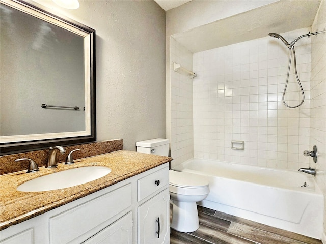 full bathroom featuring vanity, tiled shower / bath combo, wood-type flooring, and toilet