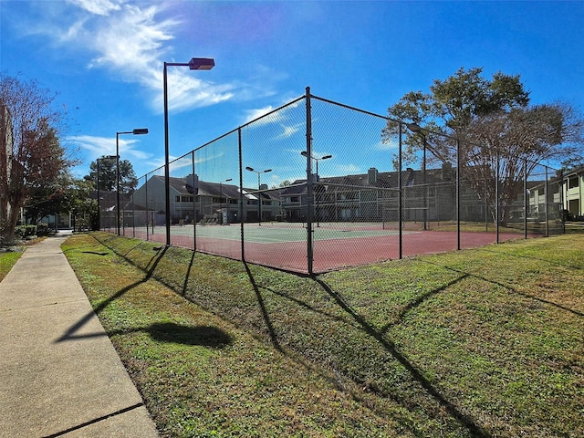 view of tennis court featuring a yard