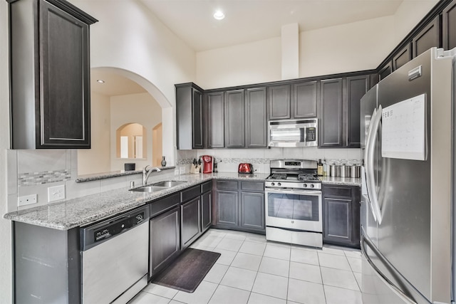 kitchen with sink, tasteful backsplash, light tile patterned floors, stainless steel appliances, and light stone countertops