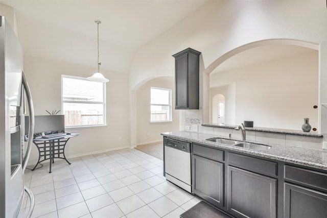 kitchen with sink, hanging light fixtures, stainless steel appliances, light stone countertops, and vaulted ceiling