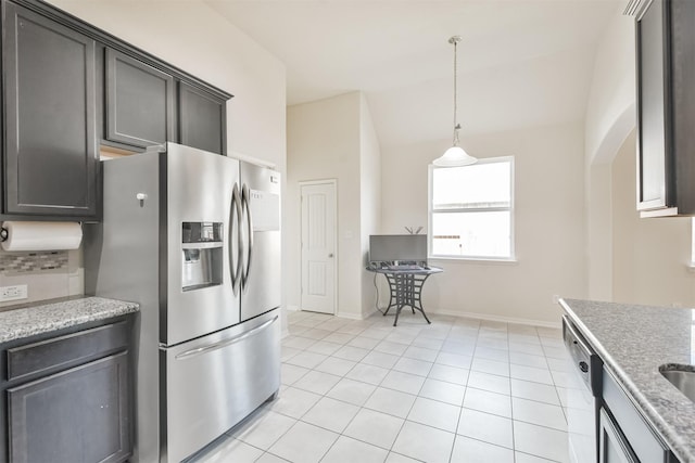 kitchen featuring vaulted ceiling, dishwasher, light tile patterned floors, light stone counters, and stainless steel refrigerator with ice dispenser