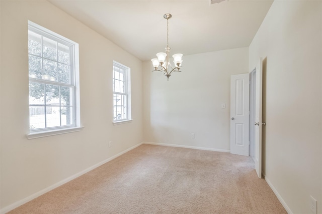 carpeted spare room featuring an inviting chandelier