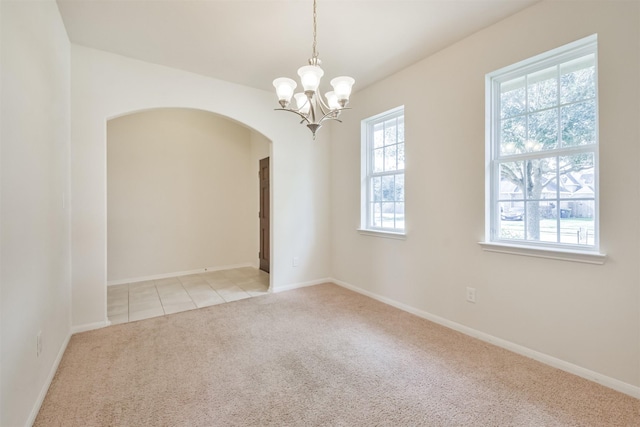 empty room featuring light colored carpet and a chandelier