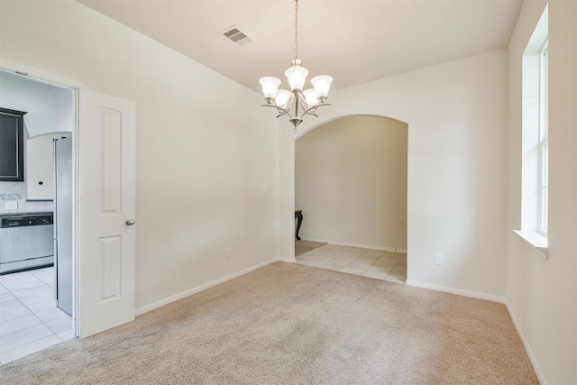 spare room with an inviting chandelier and light colored carpet