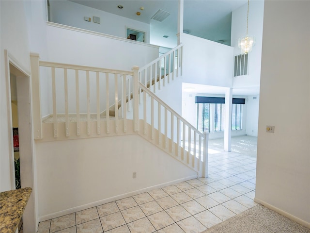 stairs featuring tile patterned flooring, a towering ceiling, and a chandelier