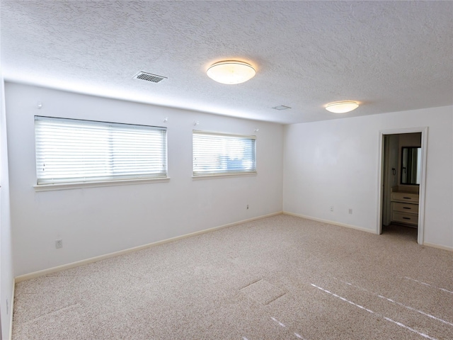 carpeted empty room with a textured ceiling