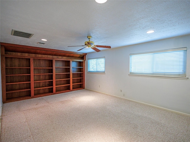 unfurnished room featuring ceiling fan, light carpet, and a textured ceiling