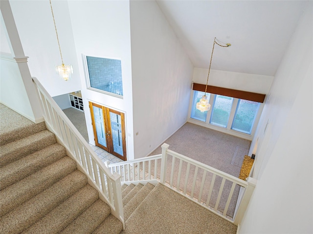 staircase featuring carpet, high vaulted ceiling, and an inviting chandelier