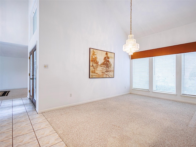 empty room featuring a high ceiling, light tile patterned floors, and a notable chandelier