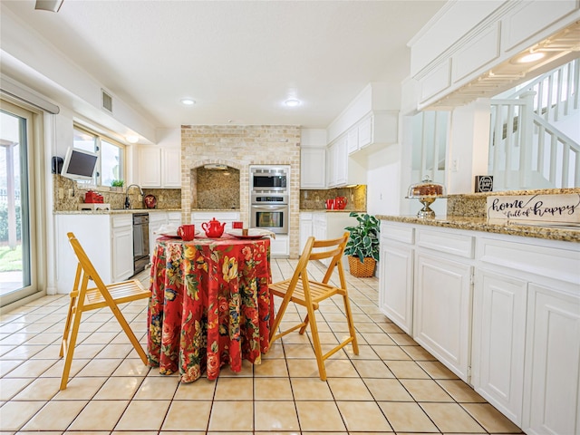 kitchen featuring light tile patterned flooring, white cabinetry, sink, decorative backsplash, and light stone countertops